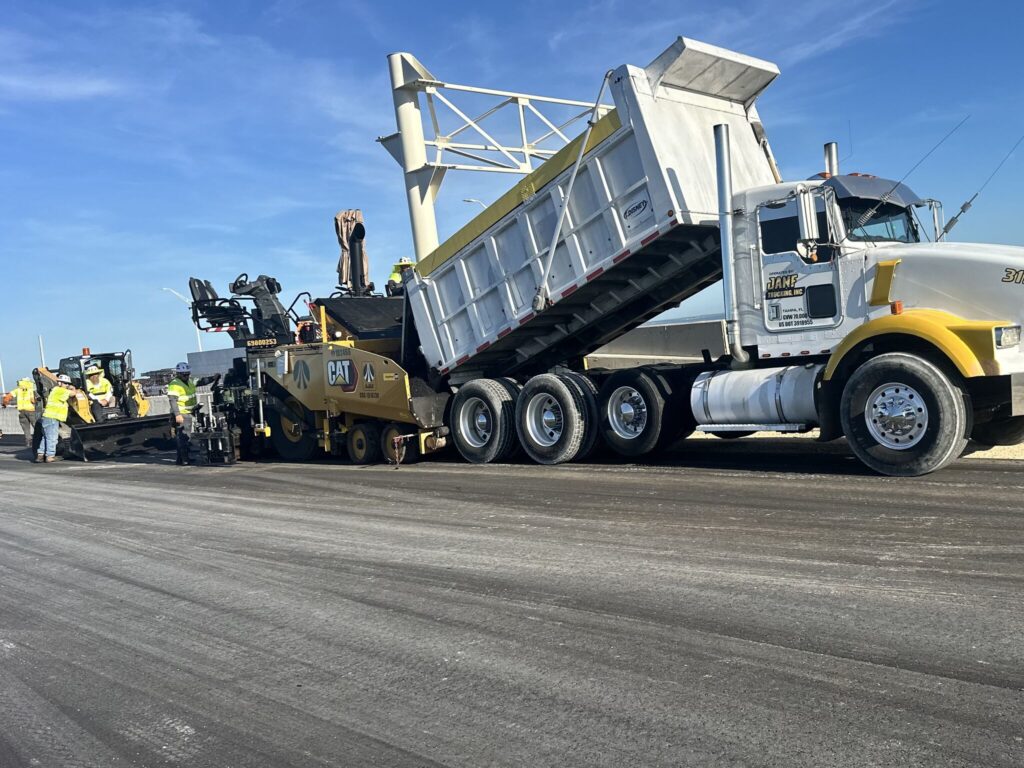 T. Disney dump truck feeding an asphalt paver