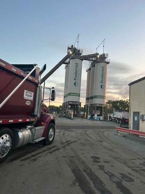 A dump truck waiting beneath the silos at an asphalt plant at first light