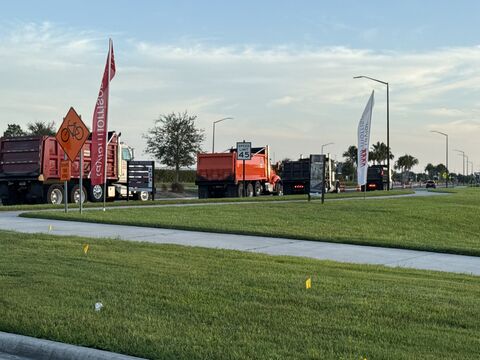 Dump trucks on a suburban road beside a share-the-road sign and a 45 mph speed limit sign